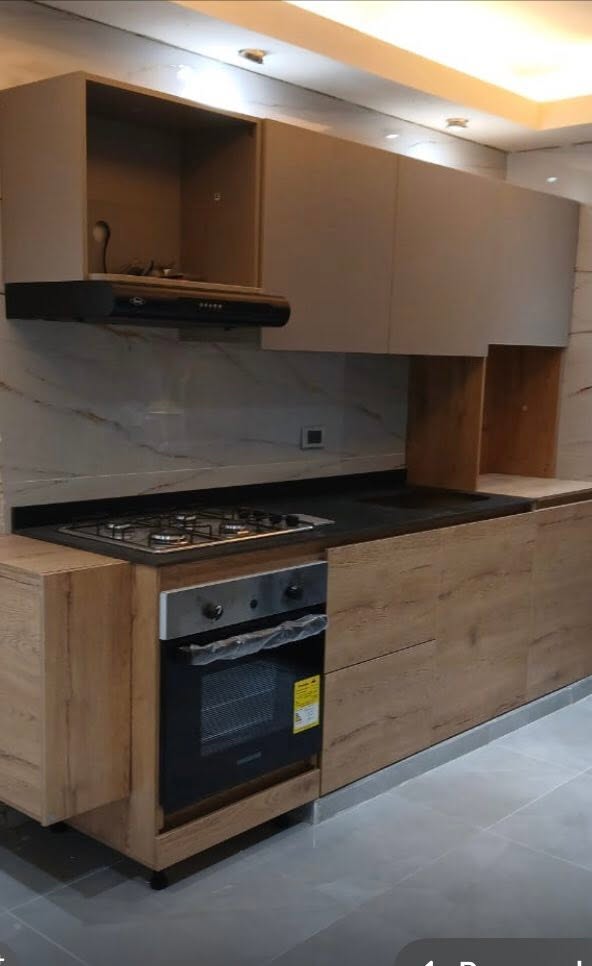 Cocina integral en roble con mesón negro, horno empotrado y campana