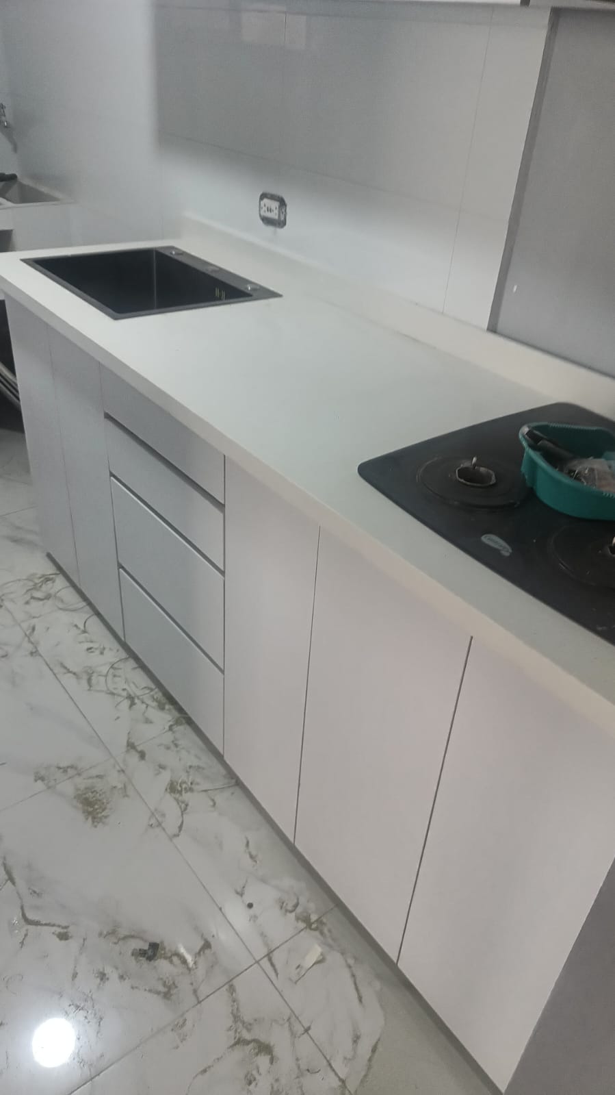Cocina blanca minimalista sin manijas con poceta negra