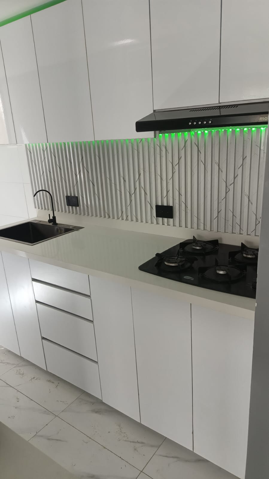 Cocina blanca alto brillo con backsplash acanalado e iluminación LED verde