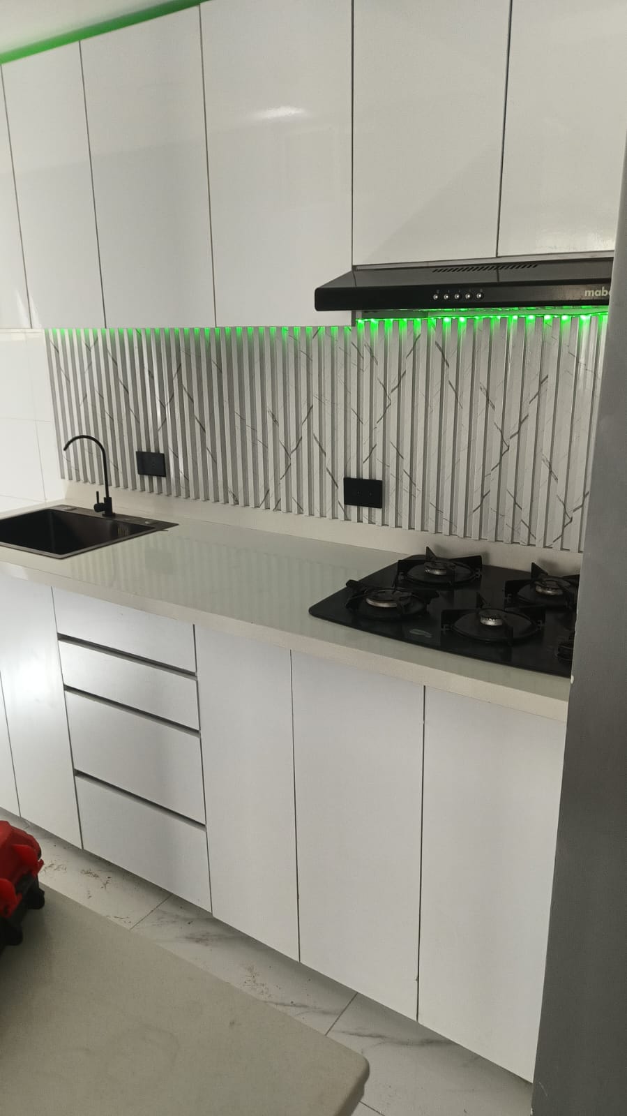 Detalle de cocina blanca con backsplash acanalado, mesón en cuarzo y luz LED